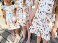 three little girls are standing next to each other wearing dresses